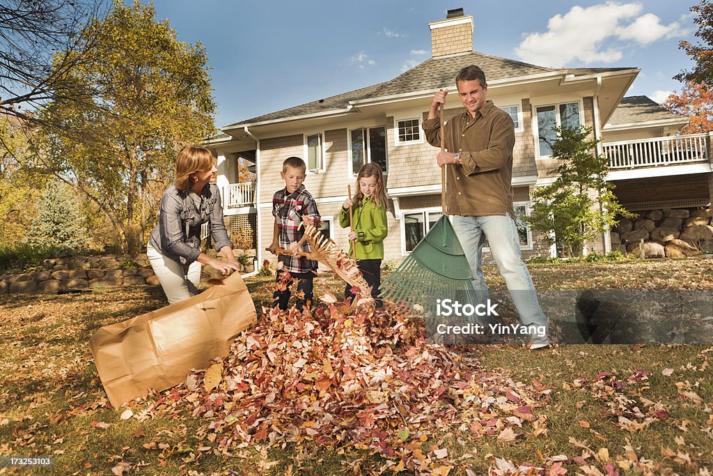 Family Doing Autumn Outdoor Leave Raking Work Together Subject: Children helping family raking fall leaves around the house and in the backyard. Rake Stock Photo