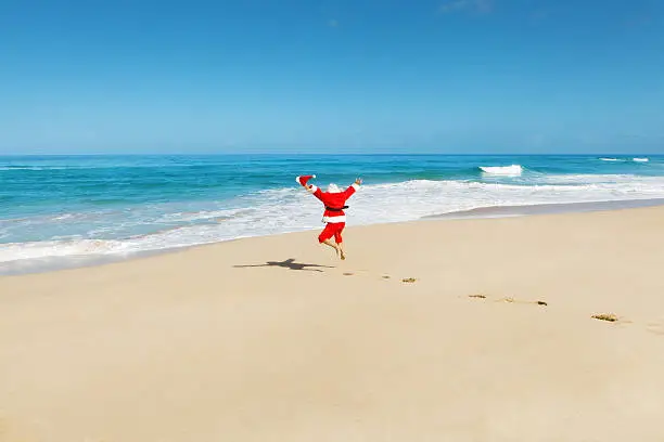 Photo of Happy Excited Jumping Santa Claus on Tropical Beach Vacation Hz