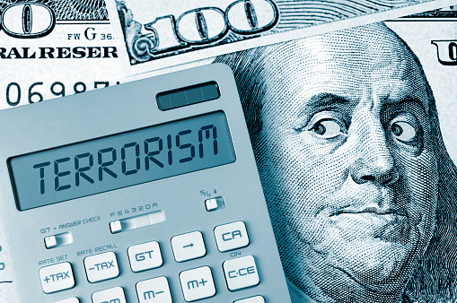 Terrorism. Benjamin Franklin looking calculator on One Hundred Dollar Bill.