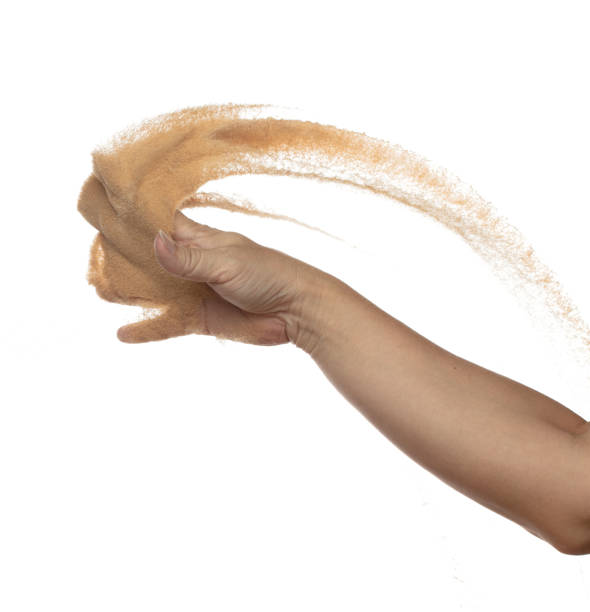 Hand throwing find sand in air. Arm wrist hand throw sand and splash explode through fingers and shape curve circle. Sand freeze stop freeze in Air. White background Isolated