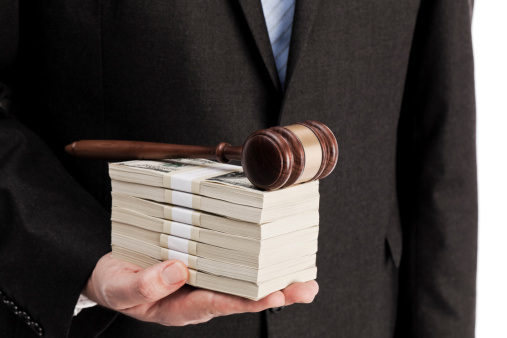 Man in suit holding stack of money and wooden gavel