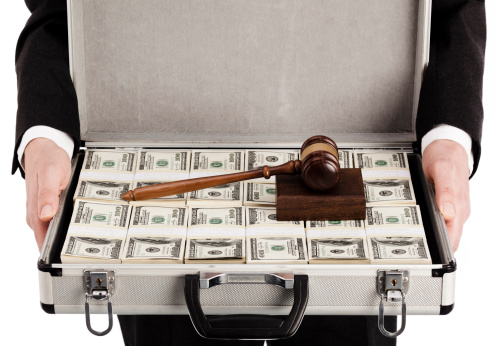 Man in suit holding briefcase full of money and gavel on top