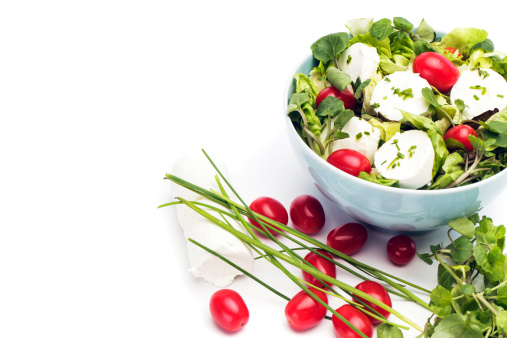 Salad made of raddish leaves green onion cherry tomatoes and mozzarella cheese