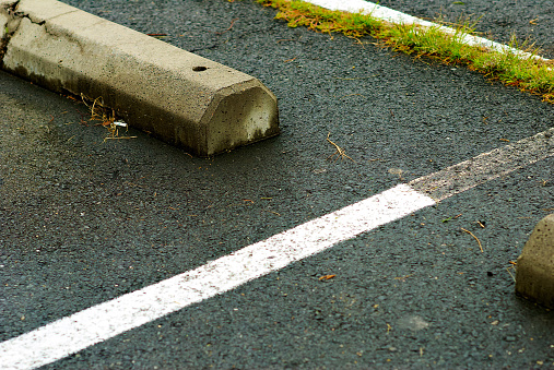 A newly painted white line covers an older one in a parking lot after a rain shower.