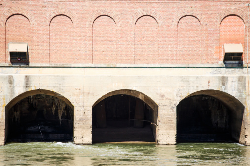 Concrete arched overflow conduits under an old brick hydroelectric dam