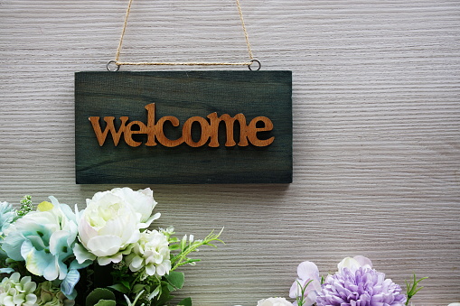 Welcome Sign and flower bouquet decoration on wooden background