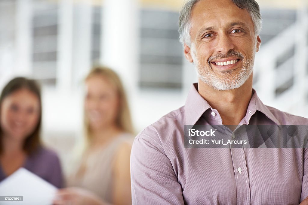 Handsome mature business leader A handsome business leader standing confidently with his team blurred in the background 20-29 Years Stock Photo