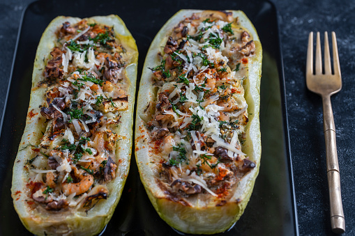 Zucchini stuffed with shrimps, vegetables and cheese. Baked zucchini boats, close up