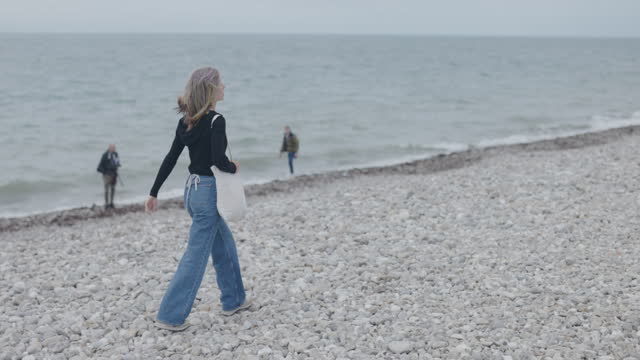 Teenage girl walking on Lyme Regis Fossil Beach in Dorset, United Kingdom