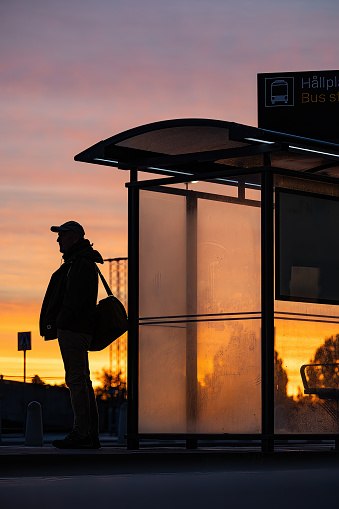 Stockholm Sweden A man in silhouette waits at a frosty busstop at Arlanda Airport at sunrise.