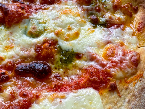 Stock photo showing close-up, elevated view of homemade mozzarella and basil pesto pizza just baked with Italian family tomato sauce recipe for topping.