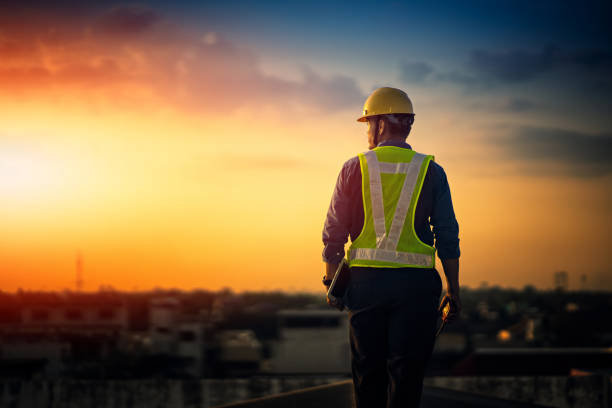 engineer on a construction site at sunset. working on the roof . - engenharia imagens e fotografias de stock