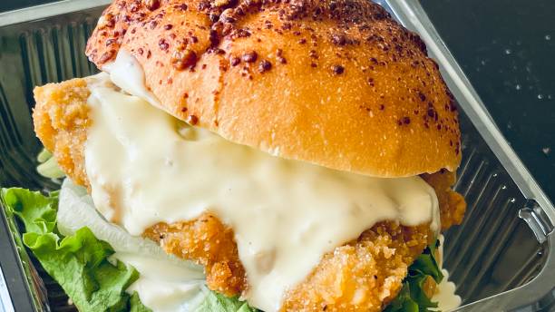 close up of delicious chicken burger, double burger with crispy chicken meat, salad and sauce in transparat container - eggs hash brown prepared potato chicken fried steak imagens e fotografias de stock