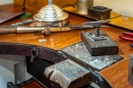 Craft workplace of a jeweler. Jewelry tools and equipment on a goldsmith wooden desk table.