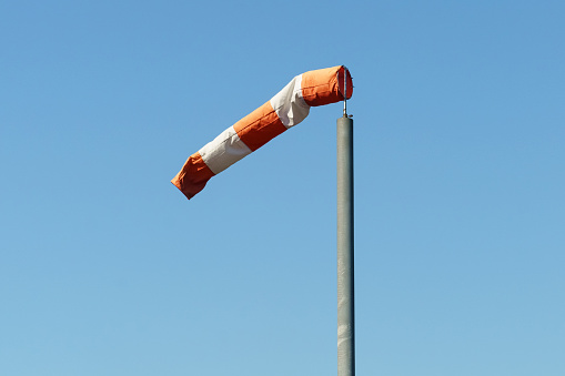 A red and white wind cone indicating the direction and strength of the wind. Strong wind, cone in horizontal position.