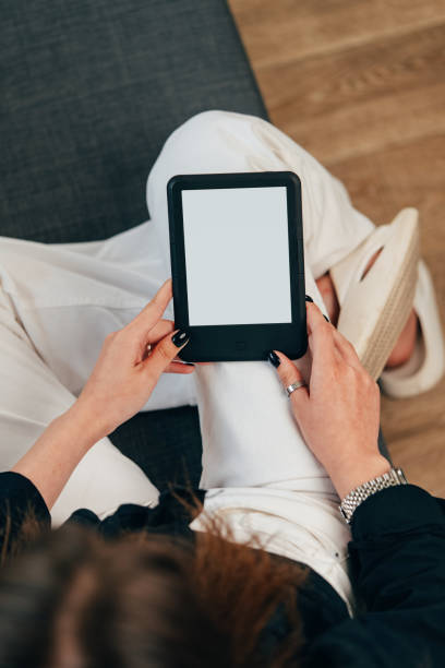 istock Young woman sitting the couch with an e-book 1732899061