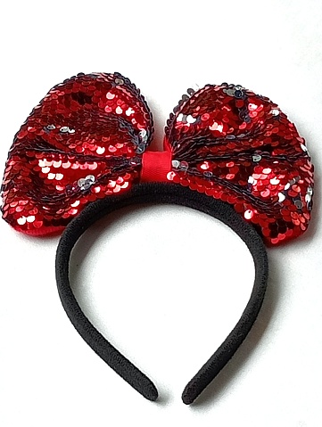 Fancy black headband red bow for parties placed on a white background. Close -up shot of the headband.