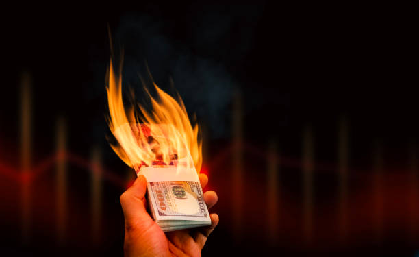 istock Burning money in hand on a dark background with copy space for text, dollar banknotes with fire blazing in hand. 1732914000