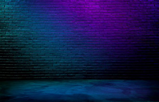 istock dark black brick wall background, rough concrete and plastered concrete floor, with gradient neon blue and purple glowing lights from above. lighting effect, blue and violet color tone. 1732922763