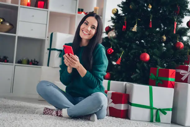 Photo of pretty sweet lady dressed knitted x-mas sweater chatting samsung apple modern gadget indoors house room.
