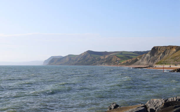 A vast body of water with a towering cliff in the Jurassic coast in Great Britain