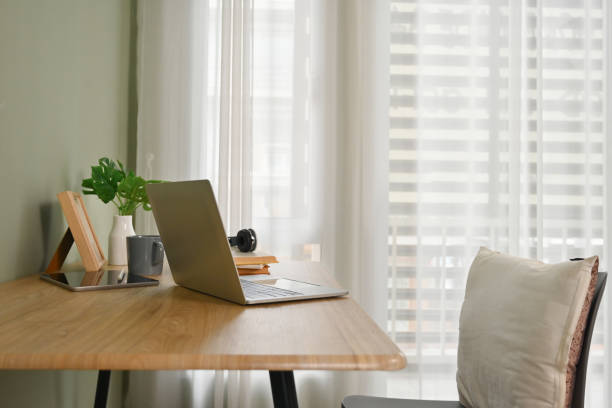 istock Comfortable home interior with laptop computer, books and potted plant on wooden table 1732970832