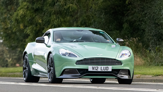 Bicester,Oxon.,UK - Oct 8th 2023: 2012 green Aston Martin Vanquish  classic car driving on an English country road.