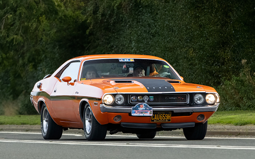 Bicester,Oxon.,UK - Oct 8th 2023: 1970 orange Dodge Challenger American  classic car driving on an English country road.