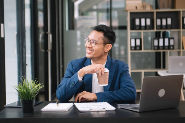 istock Young handsome man typing on tablet and laptop while sitting at the working wooden table modern office 1733025703
