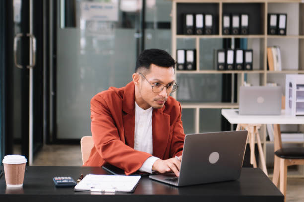 istock Young handsome man typing on tablet and laptop while sitting at the working wooden table modern office 1733025707