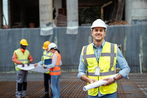 Portrait of male construction worker posing for a shot while his team is working in the background