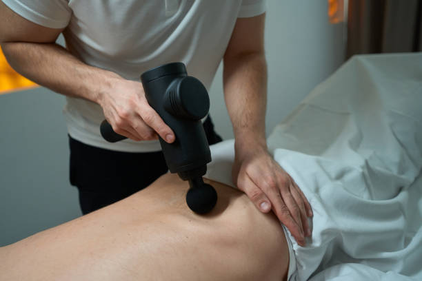 istock Physical therapist massaging client lower back with percussive massager 1733049442