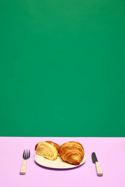 istock Crispy, fresh croissant, whole and cut in half lying on plater over green background 1733055012