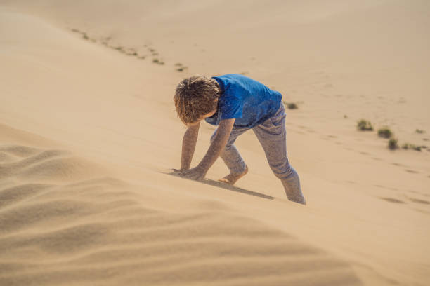 istock Boy overcomes difficulties and aspires to the purpose and dream. Boy overcomes difficulties in life as if in a desert 1733090196