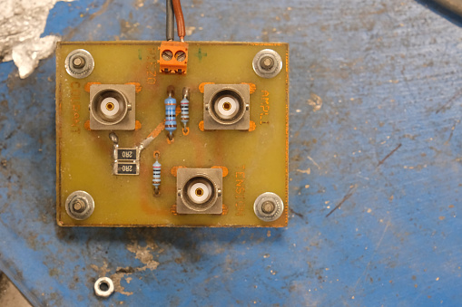 Male BNC plugs, mounted on an electronic board, on a rusted blue background