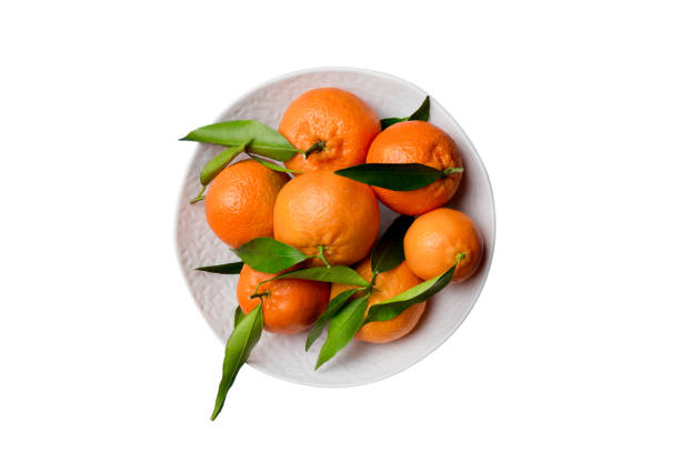 istock Fresh cutted clementines and whole mandarin over round plate isolated on white background. Food and drink ingredients preparing. healthy eating theme top view with copy space 1733104792