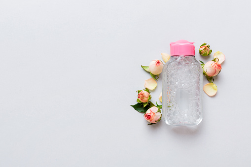 Fancy healthcare bottles for serum, micellar, tonic, toner, lotion, water and cream with rose flower. Natural oranic spa cosmetics concept. Mockup, template, Top view.