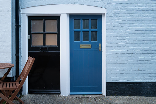Pair of wooden front doors leading to separate apartments in an English coastal town. Wooden garden furniture can be seen, for al fresco dining.