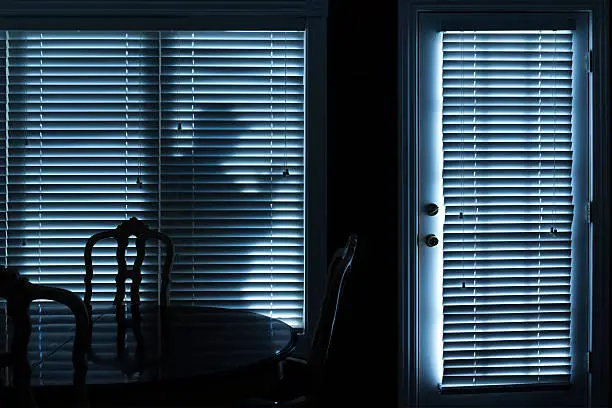 Photo of Silhouette of Burglar Sneeking Up To Backdoor At Night