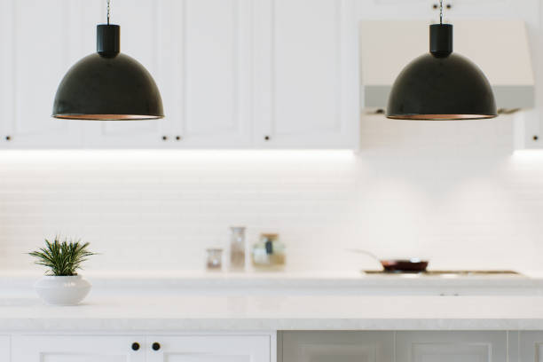 istock Modern white kitchen countertop with indoor plants and advertising space mounting your product on a blurred kitchen space in the background. 3D rendering. 1733148007