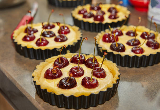 Stock photo showing close-up view of Halloween party themed food ideas. This picture is of a sliced, cherry pie with golden lattice pastry crust decorated with fondant icing black bats and fresh cherries.