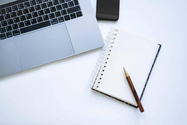 istock open notepad with blank sheet for resolutions or to do list. Laptop and smartphone on background 1733157953