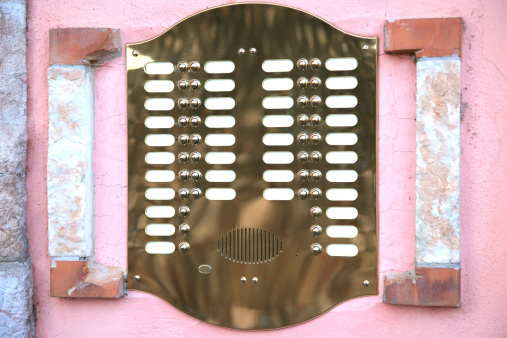 An old-fashioned doorbell on a pink wall with a plate made of brass. The labels are blank, so you can fill in whatever you want.
