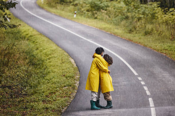 istock Embraced black couple standing on empty road during rainy day. 1733187984
