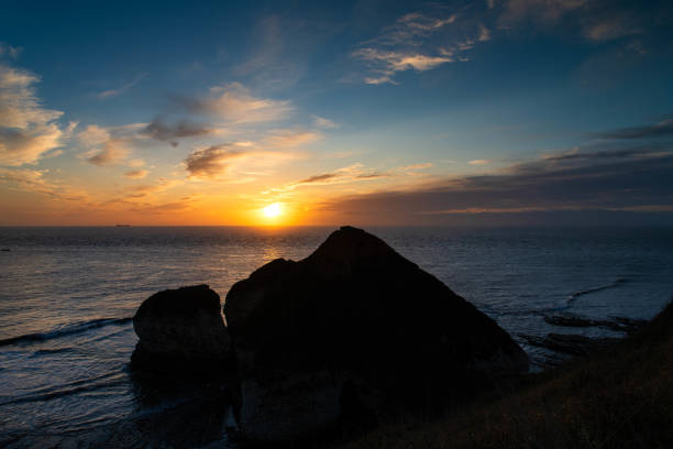 The sunrising over the silhouette of the 'Drinking Dinosaur' at Flamborough Head