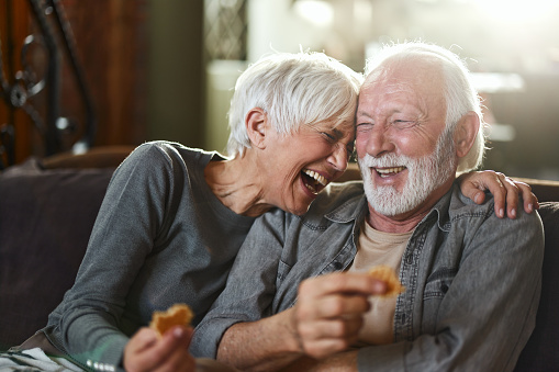 Cheerful mature couple laughing and having fun on sofa in the living room.