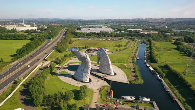 Aerial Shot Flying Behind The Kelpies, A Scottish Landmark of Horses in Falkirk Next to a Canal on a Sunny Day in Summer