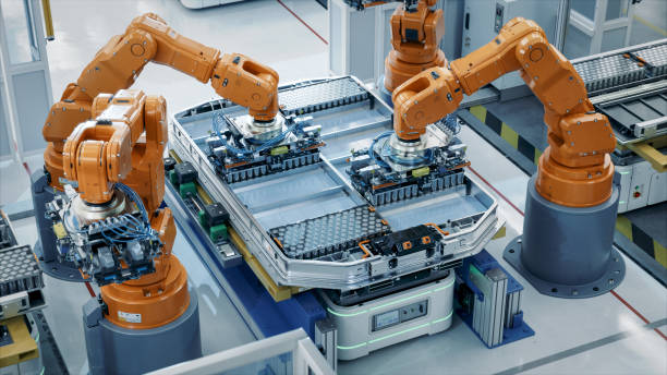istock Orange Industrial Robot Arms Assemble Skateboard style EV Battery Pack on Automated Production Line. Electric Car Smart Factory Equipped with Robotic Arms. Battery Module Installation Process Top View 1733213709