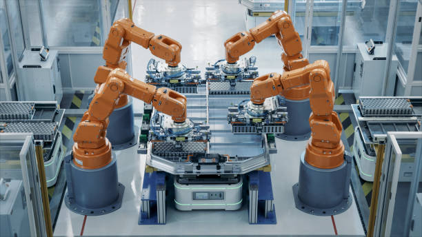 istock Orange Industrial Robot Arms Assemble Skateboard style EV Battery Pack on Automated Production Line. Electric Car Smart Factory Equipped with Robotic Arms. Top View. Automotive Battery Manufacturing. 1733213733