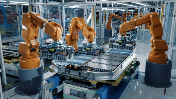 istock Advanced Orange Industrial Robot Arms Assemble EV Battery Pack on Automated Production Line. Row of Robotic Arms inside Automotive Plant Assemble Batteries. Modern Electric Car Smart Factory. 1733214249